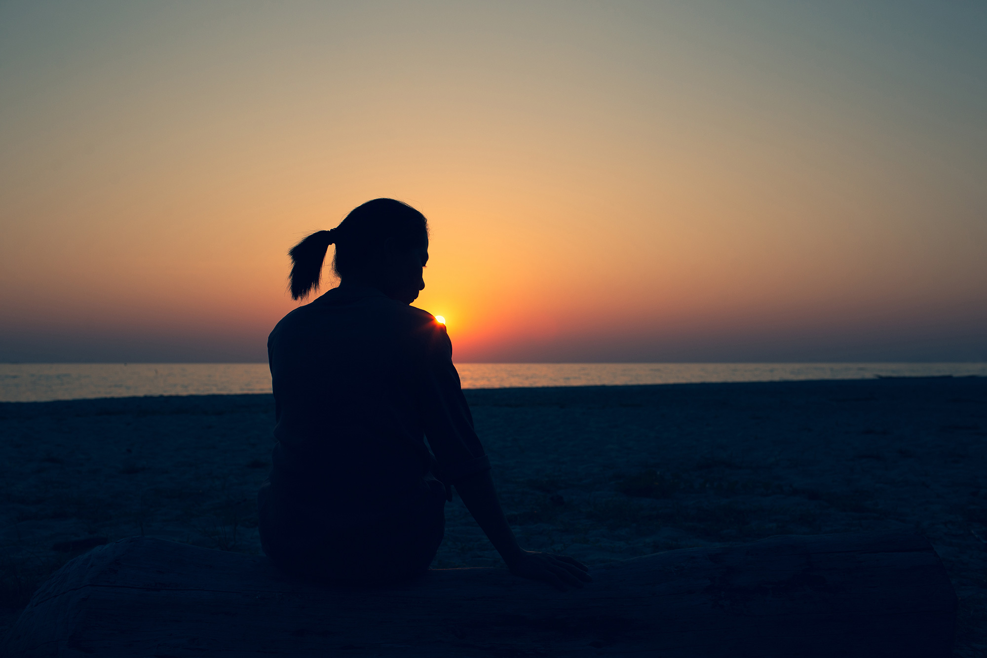 Beautiful woman sitting alone Lonely, disappointed and sad Heartbreak of life issues Style Silhouette during sunset.